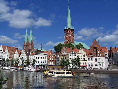 Panorma der Lübecker Altstadt mit Blick über den Fluss und drei Turmspitzen im Hintergrund