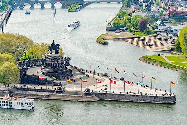 Deutsches Eck, die Gabelung von der Mosel und dem Rhein, mit dreieckigem Platz und Flaggen am Rand.