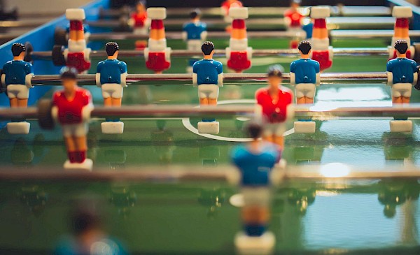 Kickerspielfeld mit bunt bemalten Fußballspielern und grünem Rasen