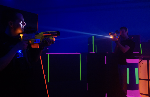 Zwei Männer, die sich mit Lasertagwaffen gegenseitig in Neonlicht anvisieren