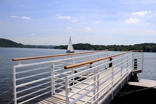 Blick auf den Baldeneysee mit einem Bootssteg und Segelbooten
