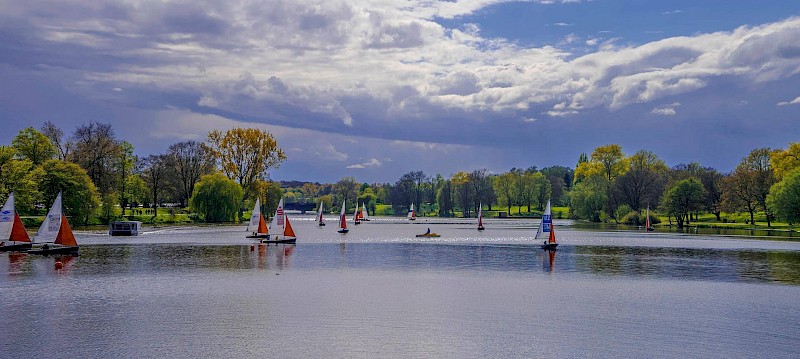 Aasee mit Segelbooten und grünen Wiesen im Hintergrund
