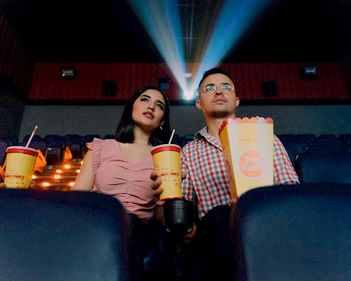 Ein Pärchen, das mit Popcorn und Cola einen Film im Kino schaut
